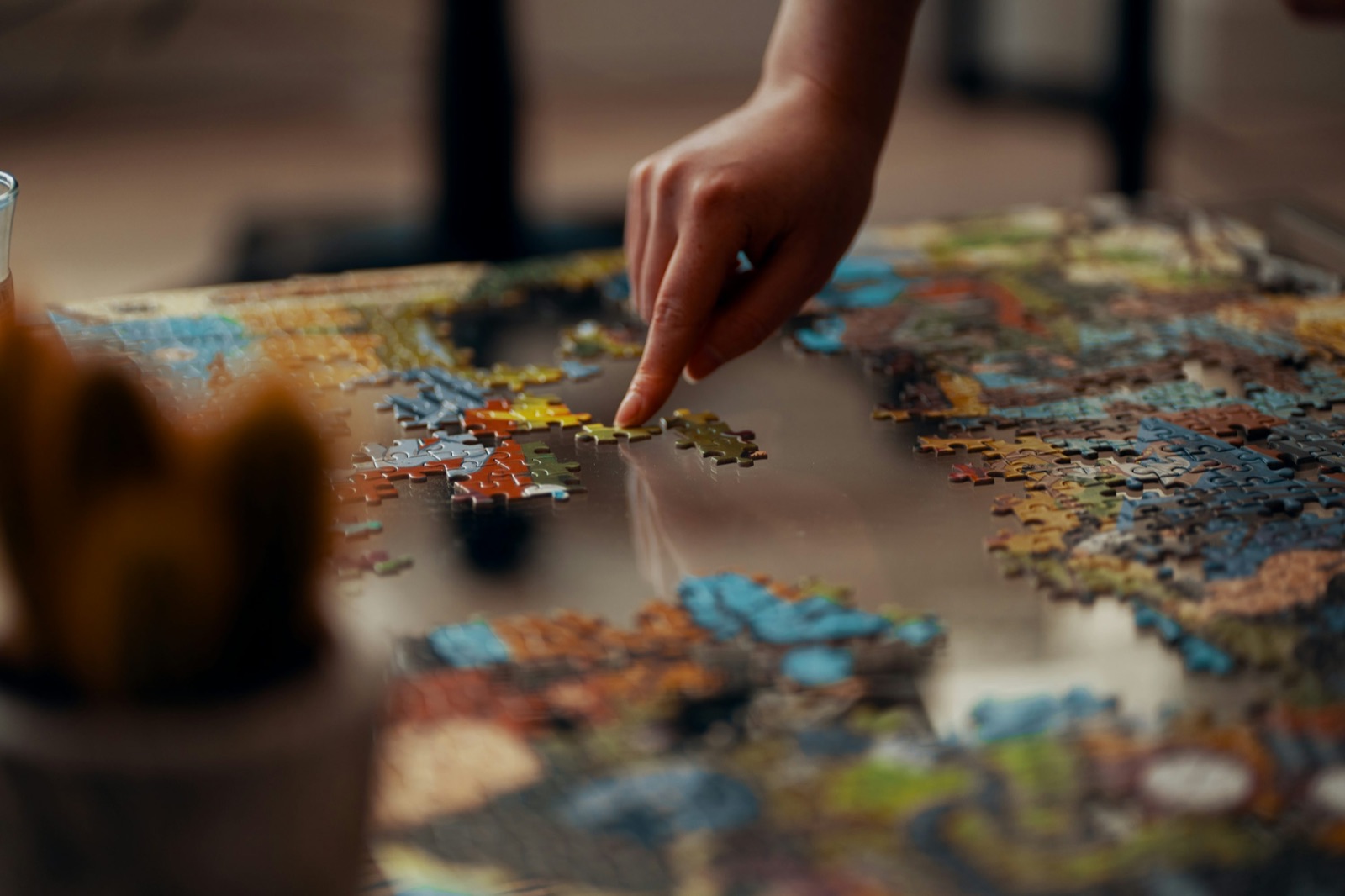 Hands placing jigsaw puzzle pieces on a table